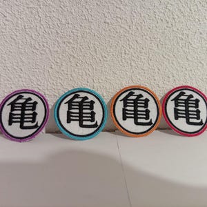 May include: Four circular patches featuring a black kanji symbol on a white background. Each patch has a different coloured border: purple, teal, orange, and pink. The patches are displayed in a row.