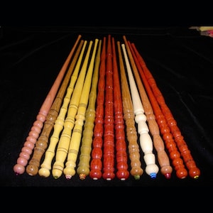 Peut inclure: Une collection de 14 baguettes en bois avec diff&eacute;rentes nuances de bois et des accents d&eacute;coratifs. Les baguettes sont dispos&eacute;es en rang&eacute;e, les pointes pointant vers la droite.
