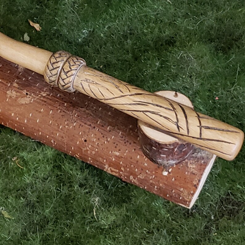 Peut inclure: Une canne de marche en bois avec un motif sculpt&eacute; et un enroulement en cuir tress&eacute; en haut.