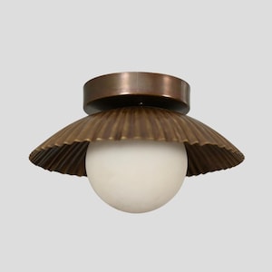 May include: A ceiling light fitting with a bronze finish and a white globe. The fitting has a decorative, scalloped shade.