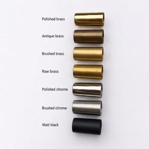 May include: A vertical column of seven cylindrical metal sleeves in various finishes, labeled from top to bottom: Polished brass, Antique brass, Brushed brass, Raw brass, Polished chrome, Brushed chrome, and Matt black. Each sleeve is identical in shape.