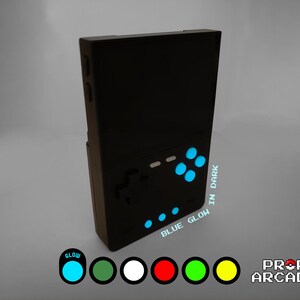 Könnte beinhalten: Eine schwarze Handheld-Videospielkonsole mit blauen, im Dunkeln leuchtenden Knöpfen und einem Bildschirm. Der Text "BLUE GLOW IN DARK" ist auf der Seite der Konsole aufgedruckt.