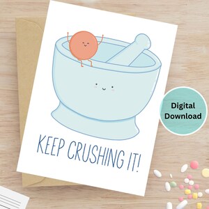 May include: A greeting card featuring a cartoon illustration of a mortar and pestle with a smiling orange character. The card has the phrase "KEEP CRUSHING IT!" printed in blue. A digital download label is visible.