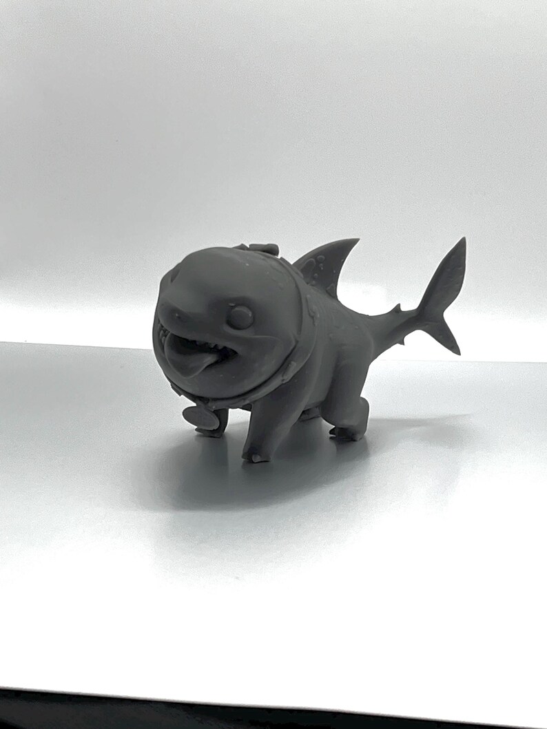 Peut inclure: Une figurine de requin en 3D imprim&eacute;e en gris, avec un collier, marchant &agrave; quatre pattes.