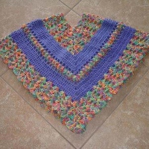 May include: A purple crochet poncho with a colourful crocheted border. The border is made of different coloured yarn, including orange, yellow, green, and blue.