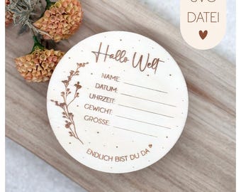May include: A round wooden disc with engraved text and lines for recording baby details. The disc includes the words "Hallo Welt" and "Endlich bist du da". It has space for name, date, time, weight, and size.