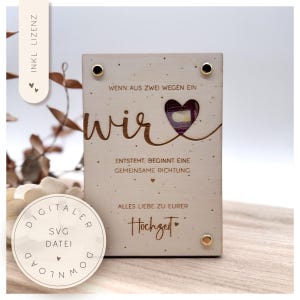 May include: A wooden plaque with the German text "Wenn aus zwei Wegen ein wir entsteht, beginnt eine gemeinsame Richtung. Alles Liebe zu eurer Hochzeit." The word "wir" is in a decorative font with a heart. Includes a digital SVG download.