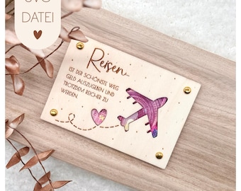 Puede incluir: Un letrero de madera con un avión rosa recortado y el texto "Reisen... ist der schönste Weg Geld auszugeben und trotzdem reicher zu werden." El letrero tiene un corazón con un patrón rosa y blanco.