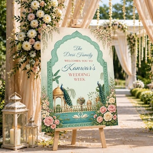 Op de afbeelding: Een welkomstbord voor een bruiloft op een houten ezel. Het bord heeft een sierlijk ontwerp met pauwen, bloemen en de tekst "The Desi Family Welcomes you to Kanwar's Wedding Week."