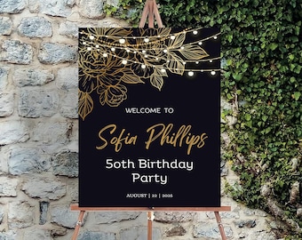 Può includere: Un cartello di benvenuto nero con lettere dorate e dettagli floreali. Il cartello recita "Benvenuti a Sofia Phillips 50° compleanno August 22 2025".