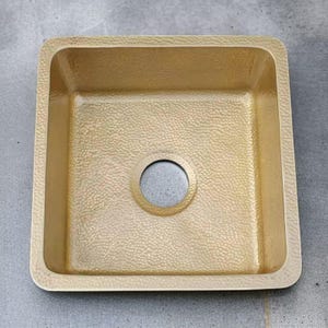 May include: A gold hammered square kitchen sink with a single drain hole.
