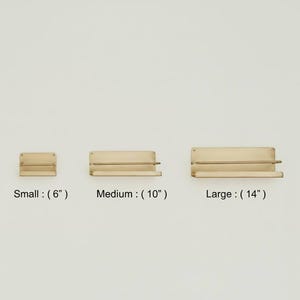 K&ouml;nnte beinhalten: Drei Holzregale in verschiedenen Gr&ouml;&szlig;en: klein (15 cm), mittel (25 cm) und gro&szlig; (36 cm). Jedes Regal hat eine rechteckige R&uuml;ckwand und eine untere Stange. Der Text "Small", "Medium" und "Large" ist darunter.