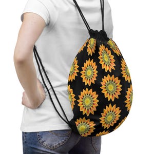 May include: A black drawstring bag with a repeating pattern of orange and yellow sunflowers. The bag is being worn by a person.