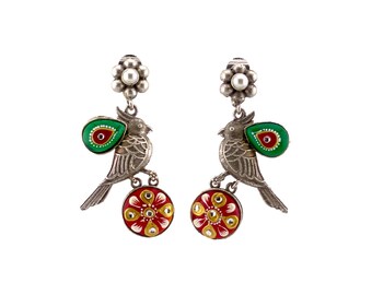 May include: Silver earrings with a bird design, green and red enamel accents, and a pearl detail.