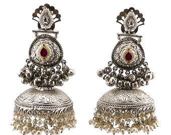 May include: Silver earrings with a pink stone and pearl accents. The earrings have a traditional Indian design with intricate details.