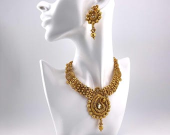 May include: A gold necklace and earrings set with intricate floral designs and a large, pear-shaped stone pendant.
