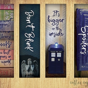 May include: Four Doctor Who themed bookmarks. The first bookmark features a stack of books with the text "You want weapons? We're in a library! Books! The best weapons in the world". The second bookmark features a blue and grey image of the Weeping Angel with the text "Don't Blink". The third bookmark features a blue police box with the text "It's bigger on the inside". The fourth bookmark features a blue police box with the text "Spoilers".