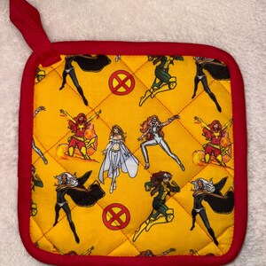 Könnte beinhalten: Ein quadratischer, gesteppter Topflappen mit leuchtend gelbem Hintergrund und einem sich wiederholenden Muster aus X-Men-Comicfiguren sowie roten X-Men-Logos. Der Topflappen ist mit einer roten Stoffeinfassung und einer kleinen roten Aufhängeschlaufe versehen.