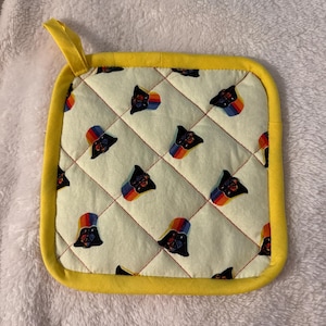 Może przedstawiać: Biały ceramiczny kubek z czarnym uchwytem i napisem "But First, Coffee" pogrubioną czcionką. Kubek jest ustawiony na rozmytym tle. Kubek ma około 10 cm wysokości.