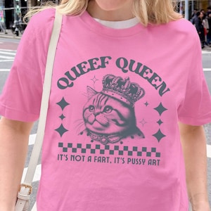 May include: Pink t-shirt with the text "QUEEF QUEEN" above a cat wearing a crown. The shirt also features the text "IT'S NOT A FART, IT'S PUSSY ART". The shirt is labeled "AZALEA".