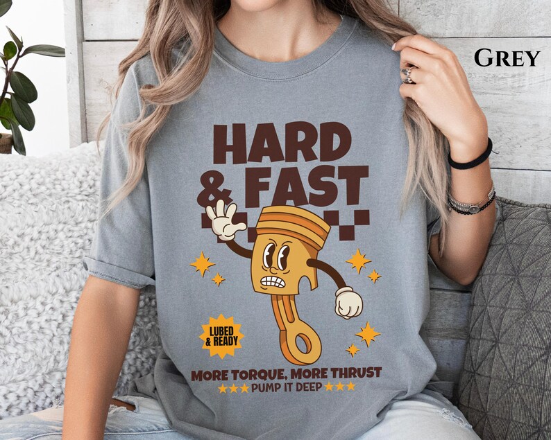 Puede incluir: Camiseta gris con una ilustraci&oacute;n de dibujos animados de un pist&oacute;n con el texto "HARD & FAST", "LUBED & READY", "MORE TORQUE, MORE THRUST" y "***PUMP IT DEEP***".