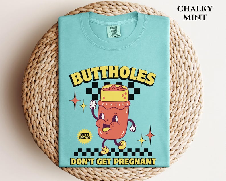 May include: A Chalky Mint colored t-shirt with the words "BUTTHOLES DON'T GET PREGNANT" and a cartoon illustration of a smiling jar with a yellow lid. The shirt also has the words "BUTT FACTS".