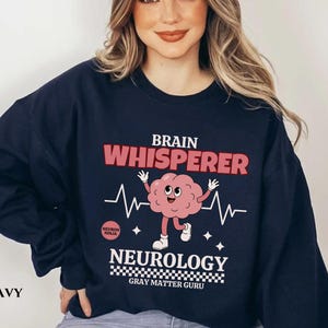 May include: Navy blue sweatshirt with a brain graphic and the text "Brain Whisperer Neurology Gray Matter Guru".