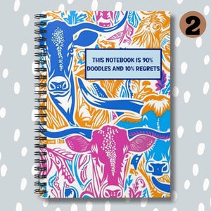 May include: A spiral bound notebook with a colorful design featuring a repeating pattern of stylized cows and floral elements. The cover has the text "This notebook is 90% doodles and 10% regrets".