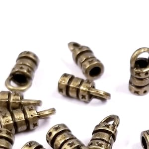 May include: A group of antique gold-toned metal end caps with a decorative design. The end caps have a small loop on one end and a cylindrical shape with a textured surface.