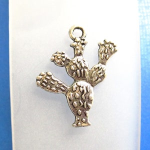 May include: Silver charm in the shape of a prickly pear cactus with detailed texture.