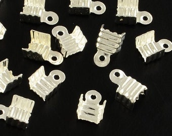 May include: A group of silver-toned metal clasps for jewelry making. The clasps are small and have a square shape with a loop on one side.