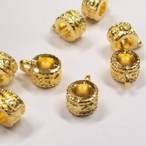 May include: Gold-toned metal bead caps with intricate designs. The bead caps have a round shape with a hole in the center for threading.