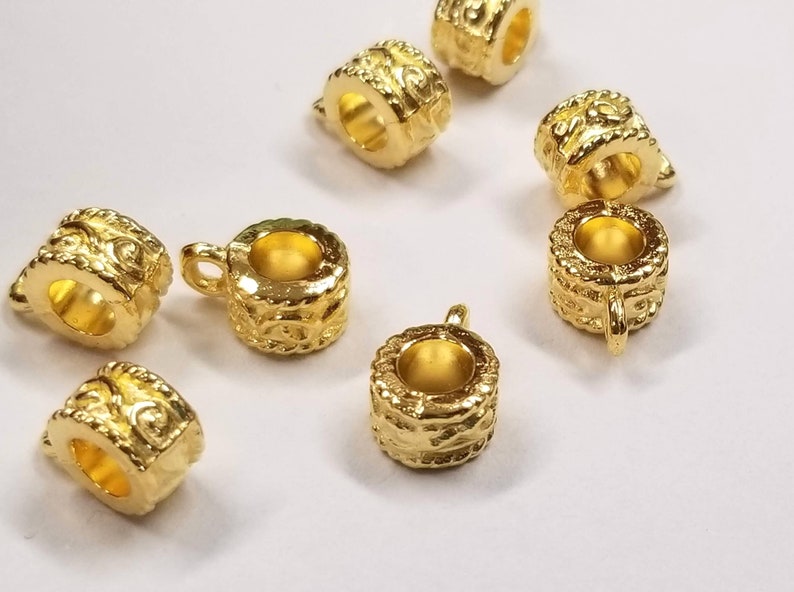 May include: Gold-toned metal bead caps with intricate designs. The bead caps have a round shape with a hole in the center for threading.