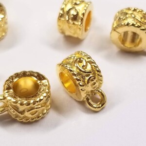 May include: Gold-toned metal bead caps with a decorative design. The bead caps have a small loop on one side and a hole on the other side.