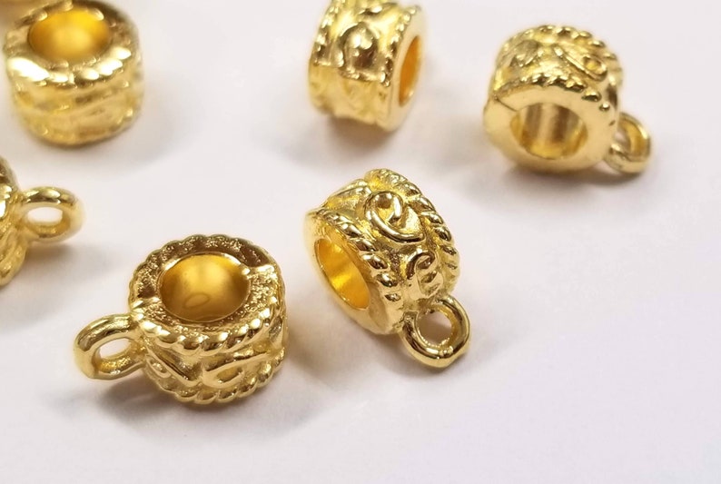 May include: Gold-toned metal bead caps with a decorative design. The bead caps have a small loop on one side and a hole on the other side.