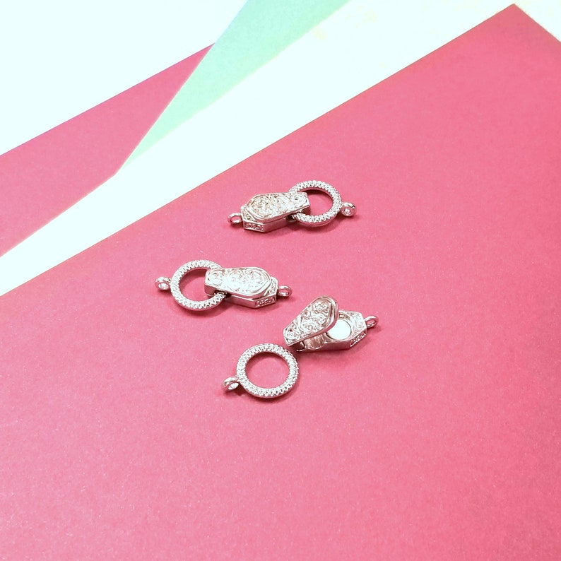 May include: Three silver-toned metal clasps with clear crystal accents. The clasps are designed to be used as jewelry closures.