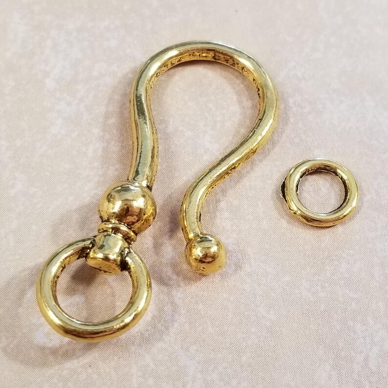 May include: Gold-toned metal swivel clasp with a round ring. The clasp has a decorative ball on each end.