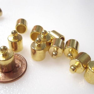 May include: A group of 10 gold-toned metal end caps with a round ball on top. The end caps are approximately 1/2 inch in diameter and 1/4 inch in height. The end caps are used to finish off the ends of cords or chains.