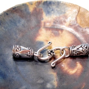 May include: Silver tone metal clasp with decorative details. The clasp is designed to be used for necklaces, bracelets, or other jewelry.