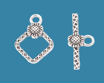 May include: Silver-toned metal clasp with a square frame and a flower design. The clasp has a loop on one side and a bar with a loop on the other side.