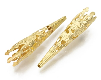 May include: Two gold metal cone-shaped bead caps with intricate filigree designs. The caps have a pointed tip and a wide, open top.