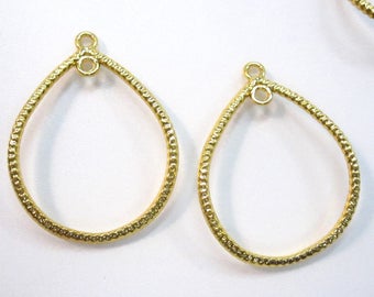 May include: Two gold-toned metal teardrop-shaped earring blanks with a textured surface. The blanks have a small loop at the top for attaching earring findings.