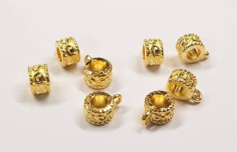 May include: Eight gold-toned metal bead caps with an ornate design. The bead caps have a small loop on one side for attaching to jewelry.