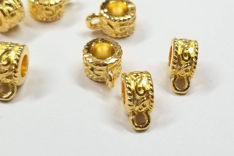 May include: Gold-toned metal bead caps with a decorative swirl design. The caps have a small loop on the bottom for attaching to jewelry.