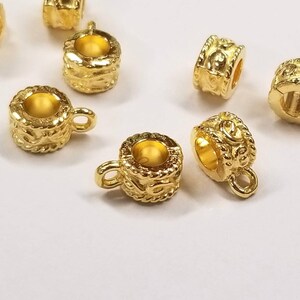 May include: Gold-toned metal bead caps with a decorative design and a loop on the side. The bead caps are perfect for adding a touch of elegance to jewelry projects.