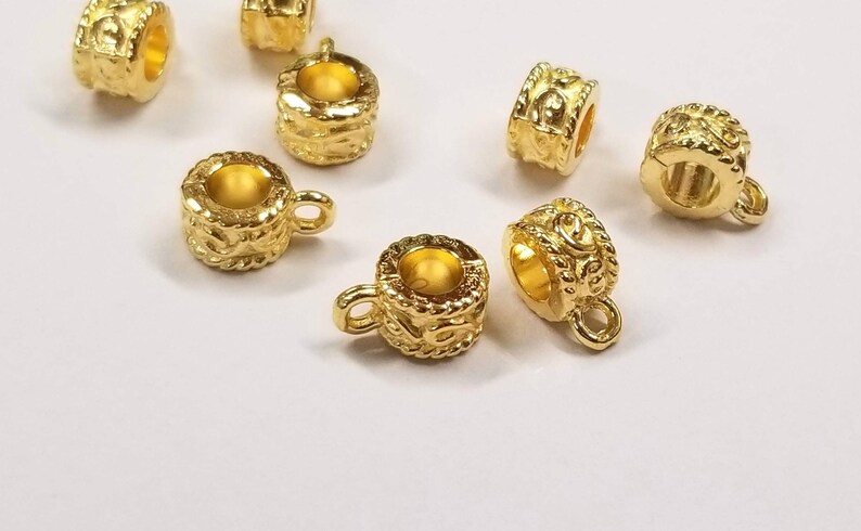 May include: Gold-toned metal bead caps with a decorative design and a loop on the side. The bead caps are perfect for adding a touch of elegance to jewelry projects.