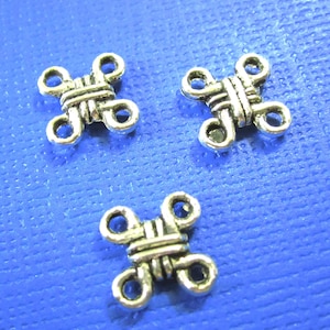 May include: Three silver metal connector charms with a woven knot design. Each charm has four loops for attaching jewelry.