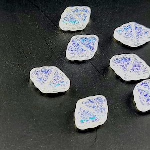 May include: Seven iridescent white glass tiles with a decorative pattern. The tiles are shaped like diamonds and have a subtle blue and purple shimmer.