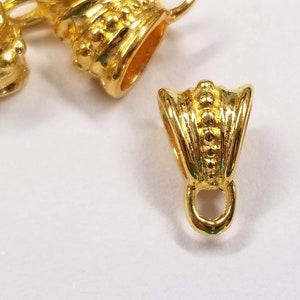 May include: Gold-toned metal pendant bail with a decorative design. The bail has a small loop at the bottom for attaching a pendant.