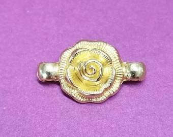May include: Gold-toned metal rose charm with a detailed design. The charm has two small loops on either side for attaching to a necklace or bracelet.